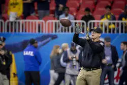 Jim Harbaugh catches a pass during Peach Bowl warm-ups